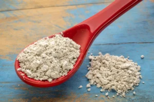 Diatomaceous earth powder in a red spoon used for natural roach control in homes.