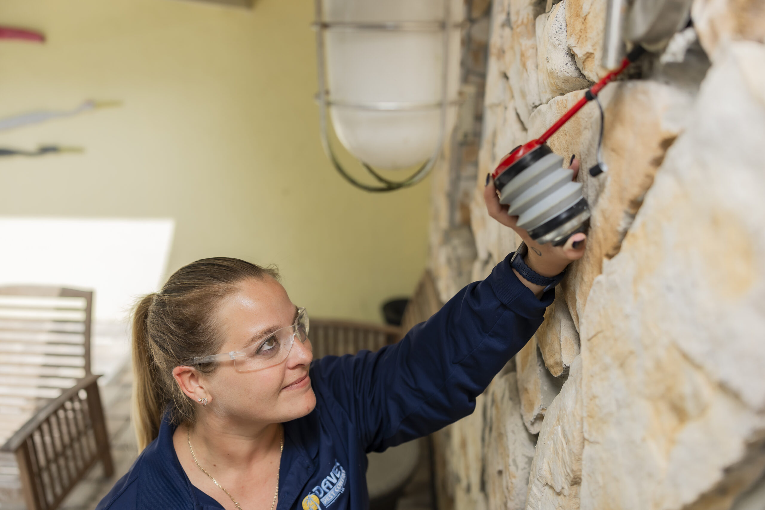 Pest control technician applying treatment to exterior wall cracks to prevent ant infestation in St. Augustine home.